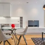 Sleek modern living room with houndstooth chairs, wooden floor, and a glass table.