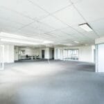Bright empty office space featuring minimalist design and glass partitions.