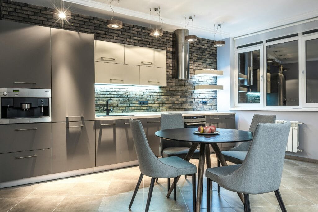 Stylish modern kitchen with brick wall and sleek dining area, showcasing minimalist design.