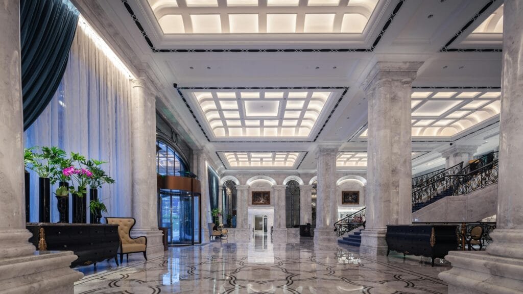 pexels-photo-16253098-16253098 Elegant hotel lobby featuring grand marble columns, high ceiling, and decorative elements in a sophisticated design.