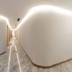 Bright modern hallway with curved walls and soft lighting, showcasing minimalist interior design.